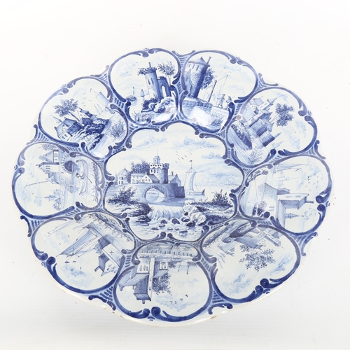 1021 - A 19th century Delft pottery cushion-shaped dish with painted panels, diameter 33cm