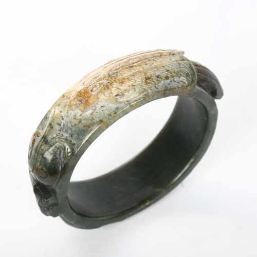 1058 - A relief carved jade bangle, internal diameter 7cm, width 2.5cm