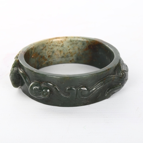 1058 - A relief carved jade bangle, internal diameter 7cm, width 2.5cm