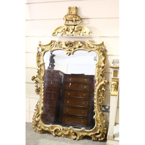 1140 - A 19th century carved giltwood-framed wall mirror, surmounted by an elephant armorial crest, overall... 