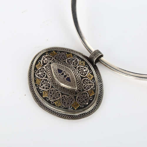 419 - A large Continental Folk Art filigree pendant, unmarked white metal settings with applied brass flow... 