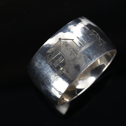 535 - ASPREY & CO LTD - a George VI silver napkin ring, planished decoration with engraved figure looking ... 