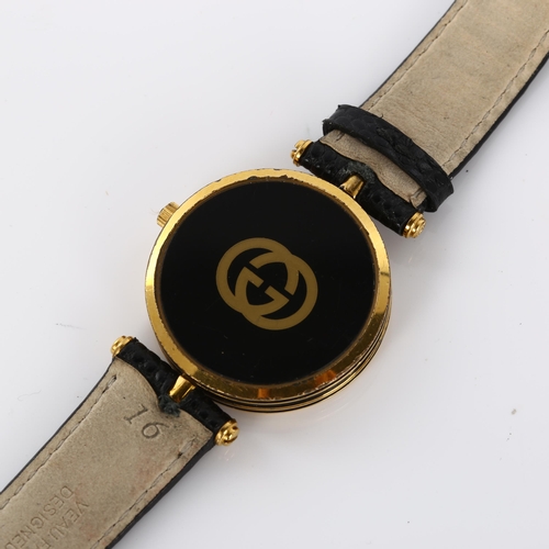 54 - GUCCI - a lady's gold plated quartz wristwatch, black dial with Roman numeral hour markers and black... 