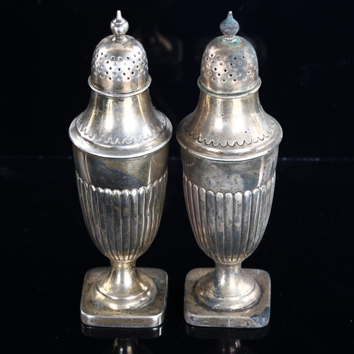 542 - A pair of Victorian silver urn pepperettes, half fluted decoration on pedestal bases, by Atkin Broth... 