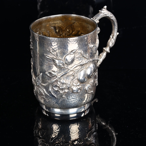 556 - An Arts and Crafts Edwardian silver half pint mug, relief embossed fruit and blossom decoration with... 