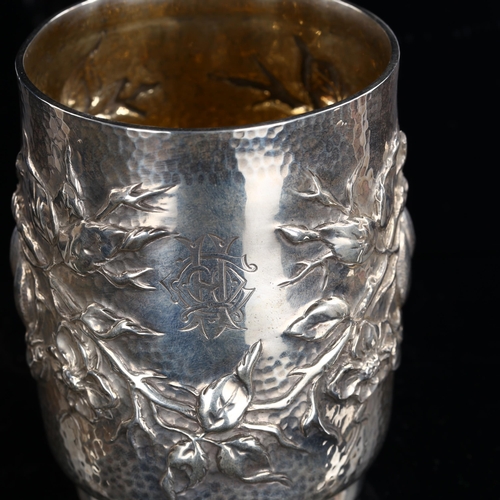 556 - An Arts and Crafts Edwardian silver half pint mug, relief embossed fruit and blossom decoration with... 