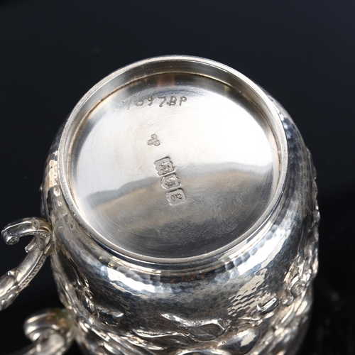 556 - An Arts and Crafts Edwardian silver half pint mug, relief embossed fruit and blossom decoration with... 