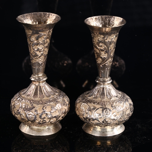 564 - A pair of Indian unmarked silver vases, allover relief embossed floral decoration, height 9.5cm, 4.1... 