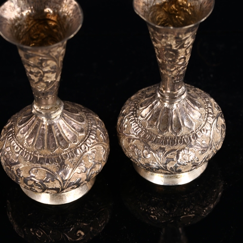 564 - A pair of Indian unmarked silver vases, allover relief embossed floral decoration, height 9.5cm, 4.1... 