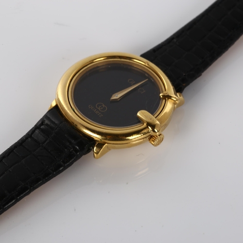 57 - GUCCI - a lady's gold plated quartz wristwatch, black dial with G-shaped case, serial no. 313600413,... 