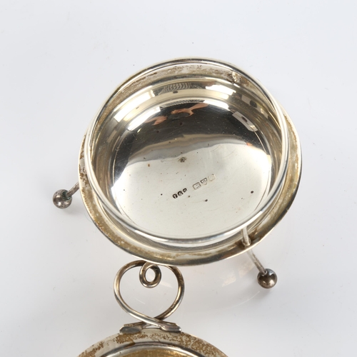 611 - An Arts and Crafts George V silver 2-handled tea strainer and stand, with wire heart-shaped handles,... 