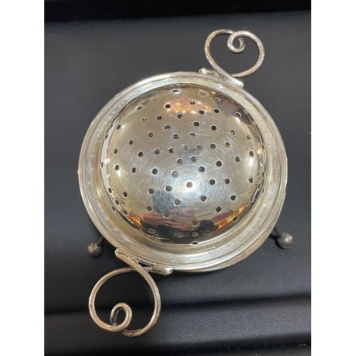 611 - An Arts and Crafts George V silver 2-handled tea strainer and stand, with wire heart-shaped handles,... 