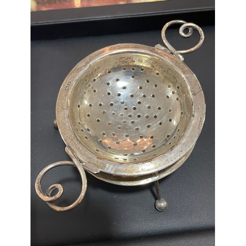 611 - An Arts and Crafts George V silver 2-handled tea strainer and stand, with wire heart-shaped handles,... 