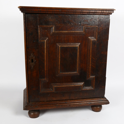 24 - A 17th century oak spice cupboard, geometric moulded door, enclosing 6 graduated drawers with pear-d... 