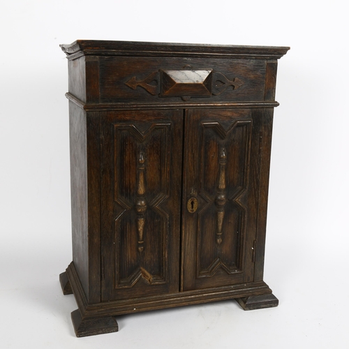 26 - A 17th century style oak table-top armoire apprentice piece, geometric moulded doors, with interior ... 