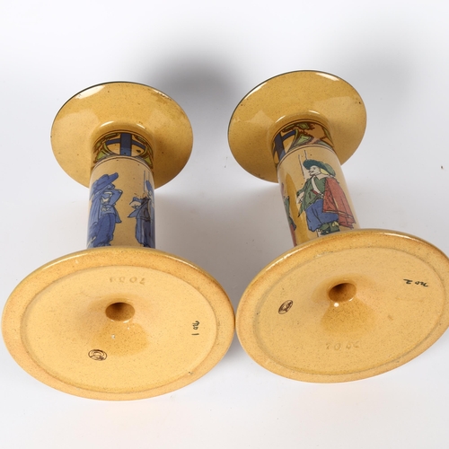 349 - A pair of stoneware candlesticks, with figures and motto decoration, height 21cm