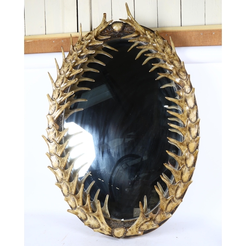 82 - A large simulated staghorn antler oval wall mirror, 106cm x 72cm