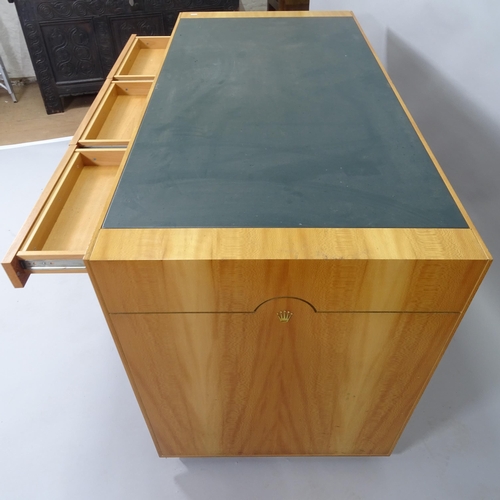 2015 - A contemporary teak kneehole writing desk, with label for Rolex, having inlaid green leather skiver ... 