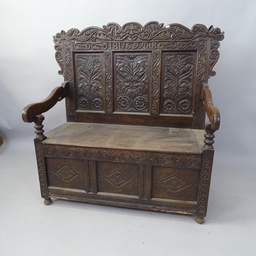 2099 - An Antique carved oak hall settle, with panelled back and lifting seat, inscribed 1697, 110cm x 120c... 