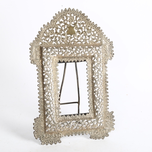 1094 - An Eastern white metal photograph frame, with allover scrolled pierced and embossed decoration