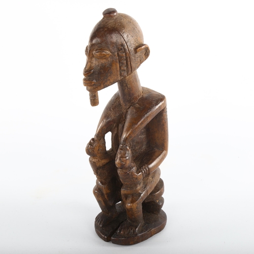 1060 - An African carved wood Tribal fertility figure feeding twins, height 19cm, early to mid-20th century