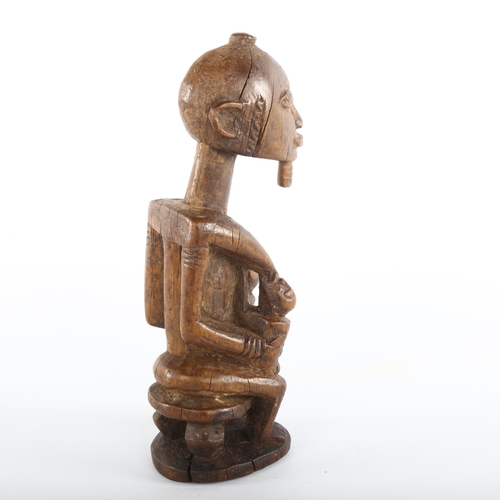 1060 - An African carved wood Tribal fertility figure feeding twins, height 19cm, early to mid-20th century