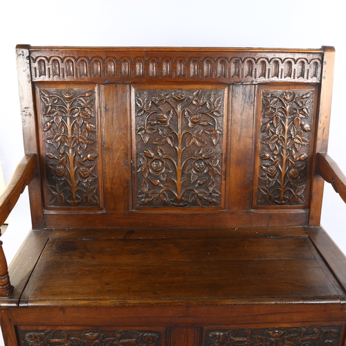 1069 - An Antique oak settle with relief carved rose design 3-panel back, rising seat and carved 2-panel fr... 