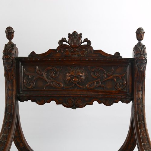 1074 - A 19th century Italian walnut X-framed armchair, with relief carved mask decoration