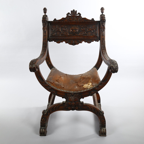 1074 - A 19th century Italian walnut X-framed armchair, with relief carved mask decoration