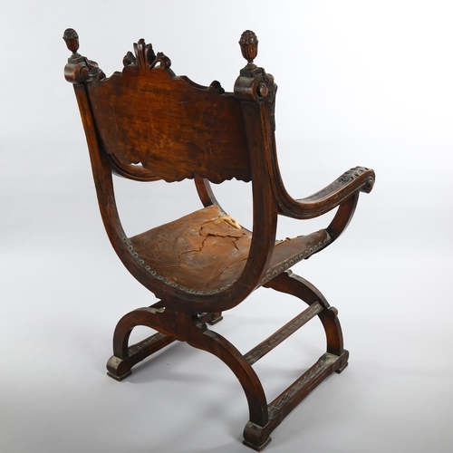 1074 - A 19th century Italian walnut X-framed armchair, with relief carved mask decoration