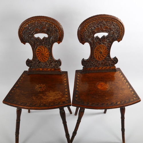 1079 - A pair of 19th century Swiss hall chairs, with ornate relief carved backs and inlaid panels, part of... 