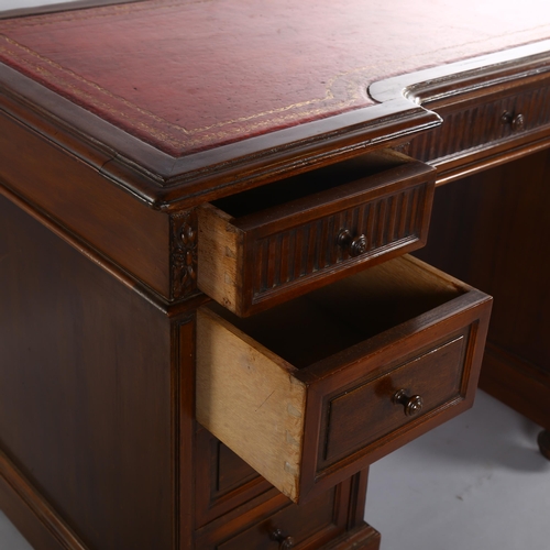 1072 - A mahogany inverted break-front pedestal desk, with inset leather top and carved frieze drawers, ear... 