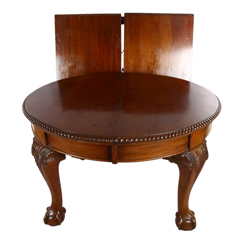 1085 - A circular mahogany wind-out dining table, circa 1900, with carved edge and ball and claw feet, 2 sp... 