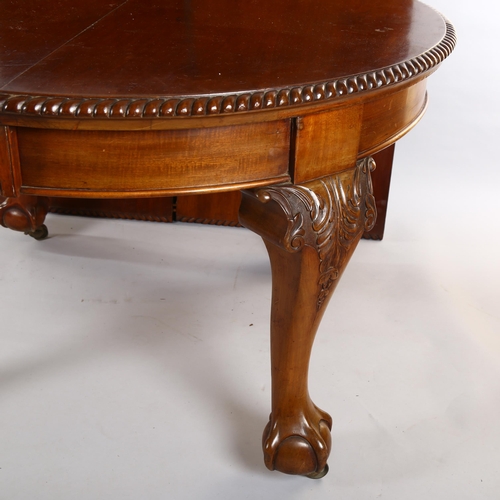 1085 - A circular mahogany wind-out dining table, circa 1900, with carved edge and ball and claw feet, 2 sp... 