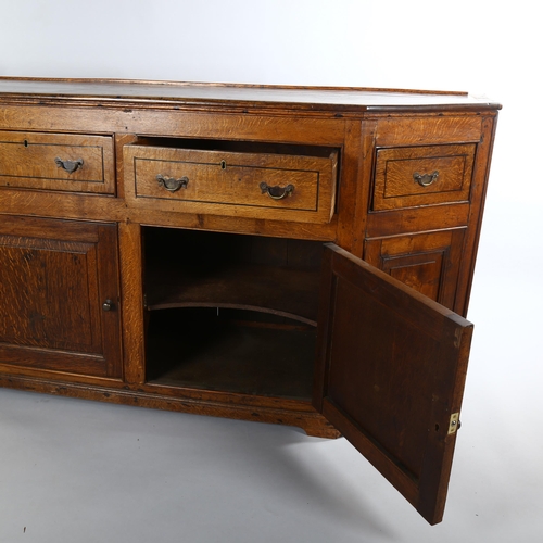 1124 - A 19th century oak dresser base, with canted ends, frieze drawers and panelled cupboards under, leng... 