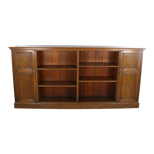 1132 - A long Edwardian oak open bookcase, with panelled cupboards to either end, length 223cm, height 107c... 