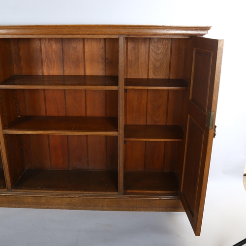 1132 - A long Edwardian oak open bookcase, with panelled cupboards to either end, length 223cm, height 107c... 