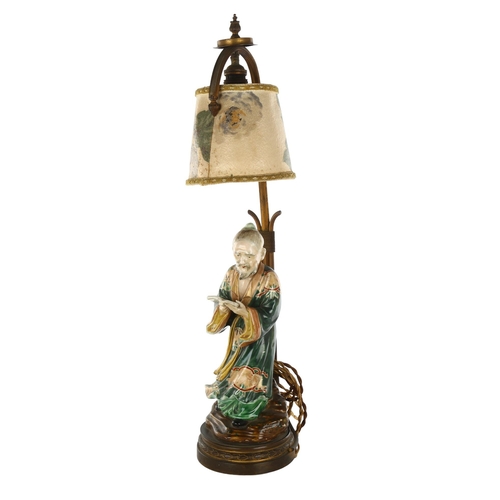 1138 - A Japanese 19th century porcelain figure of a man holding a book, mounted on a gilt-metal lamp stand... 