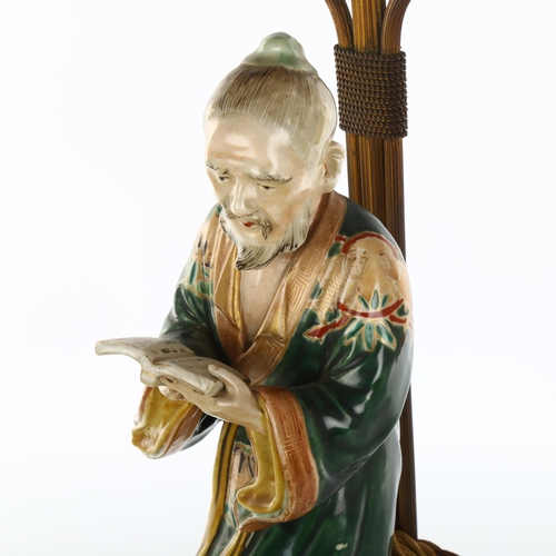 1138 - A Japanese 19th century porcelain figure of a man holding a book, mounted on a gilt-metal lamp stand... 