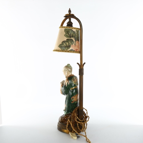 1138 - A Japanese 19th century porcelain figure of a man holding a book, mounted on a gilt-metal lamp stand... 