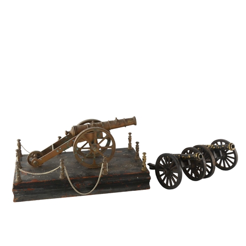 1179 - A brass model cannon on wood base, length 31cm, and a pair of smaller painted brass model cannons