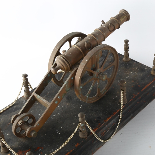 1179 - A brass model cannon on wood base, length 31cm, and a pair of smaller painted brass model cannons