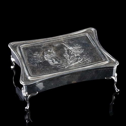 538 - A large Edwardian silver dressing table jewel box, shaped rectangular form with relief embossed figu... 