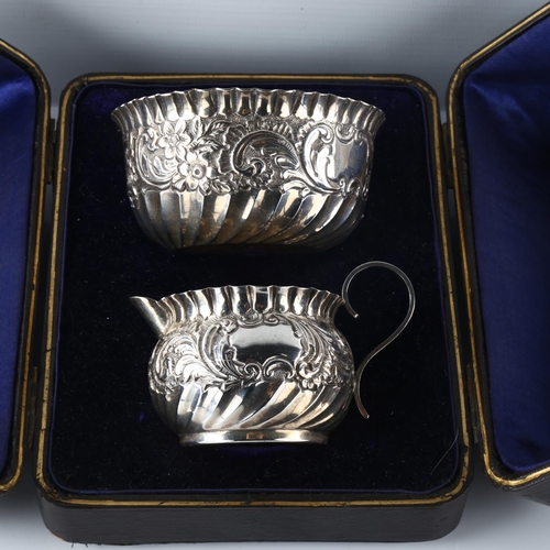 585 - A cased Victorian silver sugar bowl and cream jug set, fluted and relief embossed floral decoration,... 