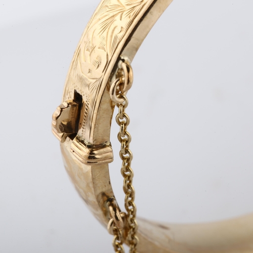 150 - A late 20th century 9ct gold hinged bangle, with engraved foliated decoration, maker's marks S and P... 