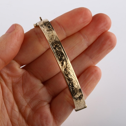 150 - A late 20th century 9ct gold hinged bangle, with engraved foliated decoration, maker's marks S and P... 