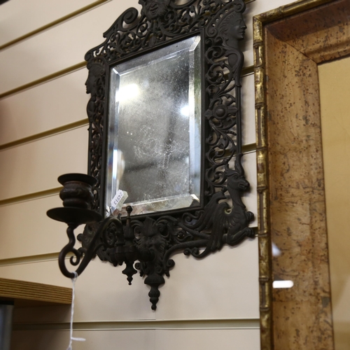 116 - A pierced and engraved cast-metal bevel-edge wall mirror, with single sconce and decorated with drag... 