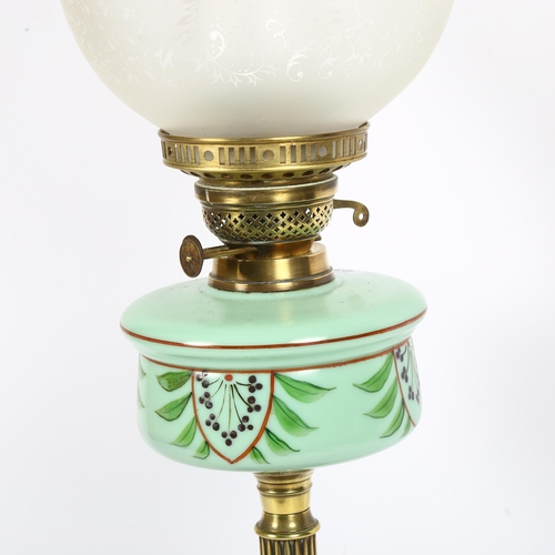 235 - A Victorian brass oil lamp, with a cranberry and clear glass etched shade and painted green glass fo... 