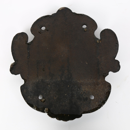 32 - A 19th century painted cast-iron heraldic plaque, decorated with saddles and stirrups, length 25cm