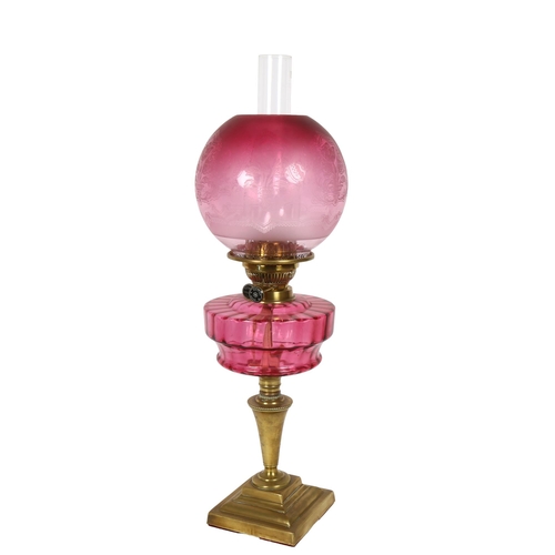 48 - A Victorian brass and cranberry glass oil lamp (Best English Make, British made), with etched shade ... 